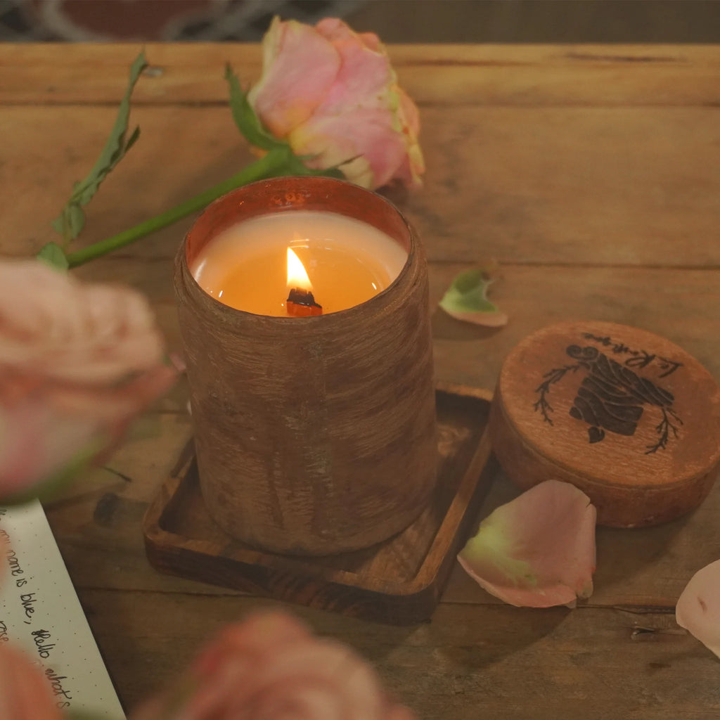 Cozy Aromatherapy Candle in a wooden holder on a wooden surface with flowers and coasters