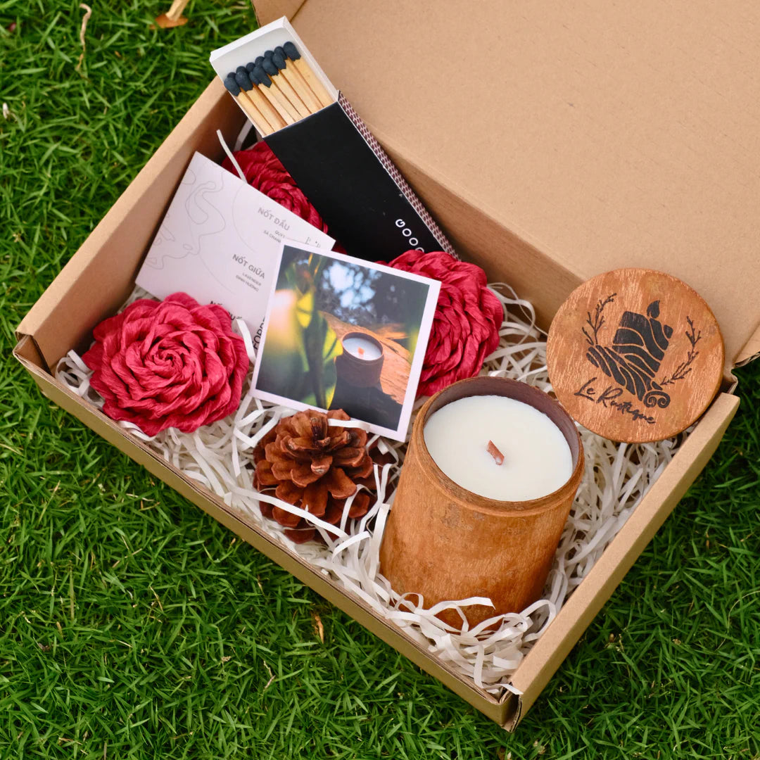 Le Rustique classic Gift box with a scented candle, matches, and decorative items on grass